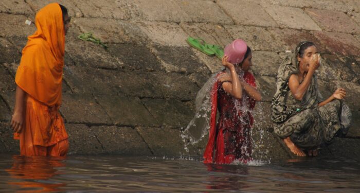 Bangladeshi women splash water on their faces nearby a less crowded ghat.