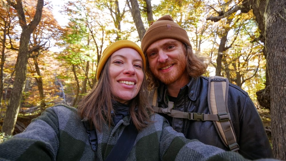 Samuel Jeffery and Audrey Bergner hiking near Laguna Verde outside Bariloche, layered in warm clothing within a sheltered Patagonian forest, illustrating how proper gear and protected terrain make hiking far more manageable despite the region’s unpredictable wind conditions.
