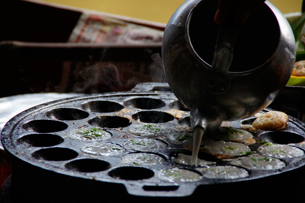 Batter is being poured into a mold being used to make Thai cakes at the Damnoen Saduak Floating Market in Bangkok, Thailand