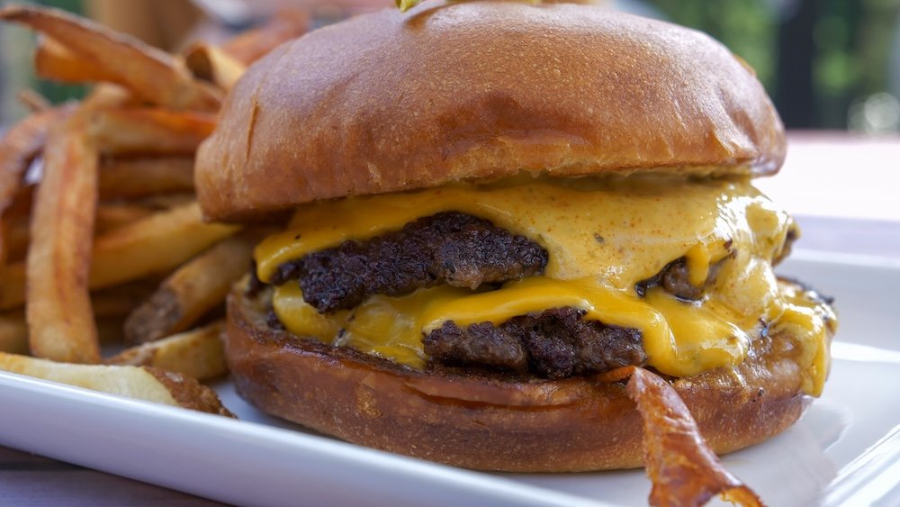Smash Wagyu burger at Bear Bistro in Island Lake Lodge, Fernie, BC Bear Bistro at Island Lake Lodge in Fernie, British Columbia, featuring the Smash Wagyu burger with double patties, melted cheese, and crispy fries, highlighting one of the most indulgent and memorable dining experiences available during a Fernie getaway.