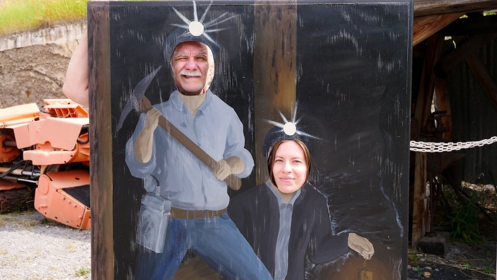 Bellevue Underground Mine Tour in Crowsnest Pass, Alberta, featuring a playful cutout display where Audrey Bergner and Daniel Bergner pose as miners with headlamps, highlighting the light-hearted moments, interactive exhibits, and why this historic site makes a fun, memorable day trip from Fernie, BC.