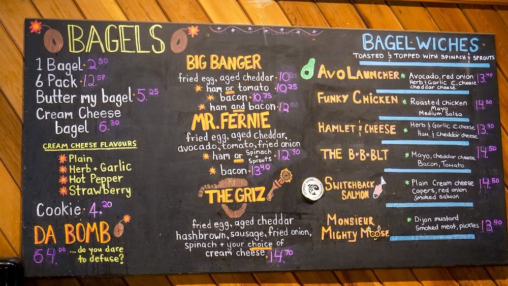Big Bang Bagels chalkboard menu in Fernie A colourful chalkboard menu inside Big Bang Bagels in Fernie, British Columbia displays a full lineup of bagels, cream cheese flavours, and creative bagelwiches, showcasing local favourites like the Big Banger, Mr. Fernie, and Switchback Salmon in the cozy mountain café.