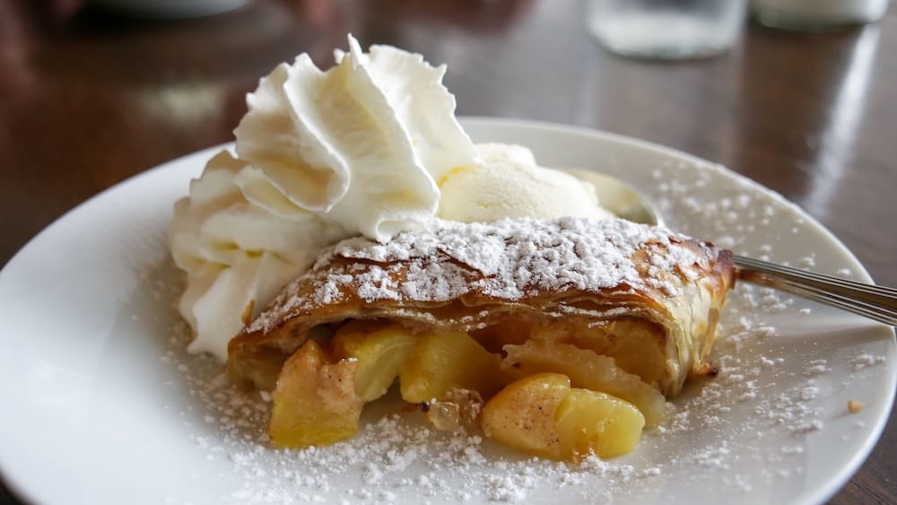 Apple Strudel Dessert at Bistro Praha in Edmonton, Alberta, Canada Apple strudel at Bistro Praha in Edmonton, Alberta, Canada, served with whipped cream, vanilla ice cream and powdered sugar on a white plate.