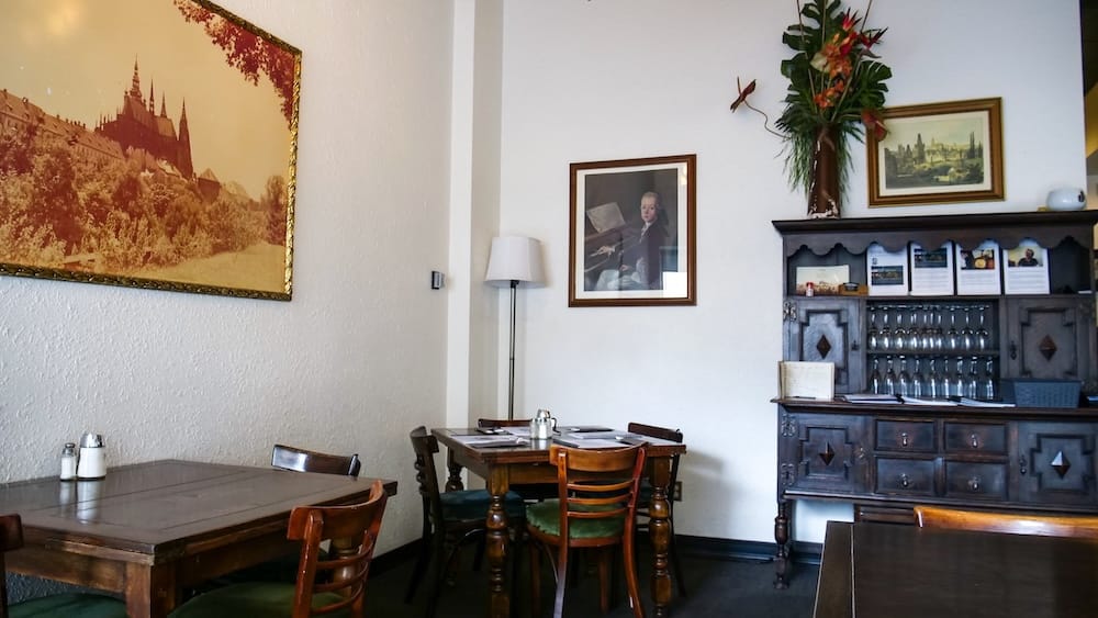 Traditional Interior of Bistro Praha Restaurant in Edmonton, Alberta, Canada Interior of Bistro Praha in Edmonton, Alberta, Canada, with wooden tables and chairs, framed European artwork, a dark wooden cabinet and traditional dining-room décor.
