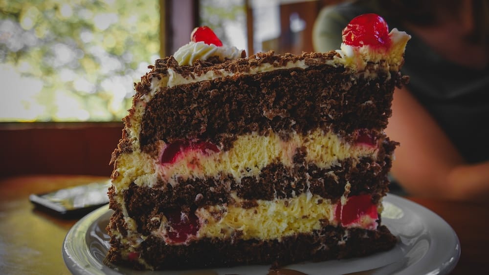 Black Forest cake slice in El Bolsón layered with chocolate sponge, whipped cream, and cherries, showcasing Patagonia’s rich dessert culture where generous portions and indulgent sweets are a core part of the local food experience
