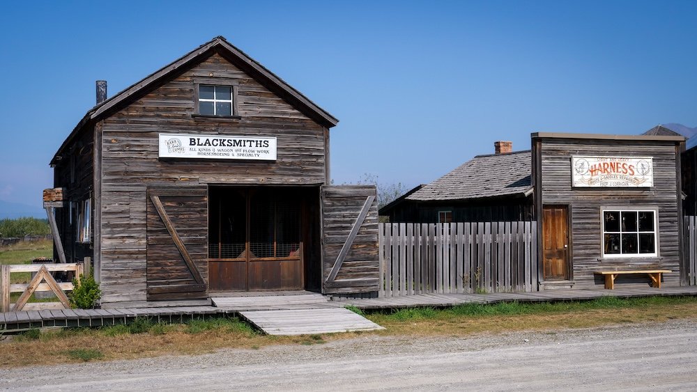 Fort Steele Heritage Town near Cranbrook, BC, showing the historic Blacksmiths building with weathered wooden siding and period signage, highlighting the hands-on, old-west atmosphere visitors experience on an easy day trip.