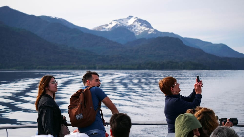 Nahuel Huapi Lake boat cruise, Bariloche, Río Negro, Argentine Patagonia Passengers on a Nahuel Huapi Lake boat cruise near Bariloche, Río Negro, Argentine Patagonia, photographing a snow-capped Andean peak from the deck.