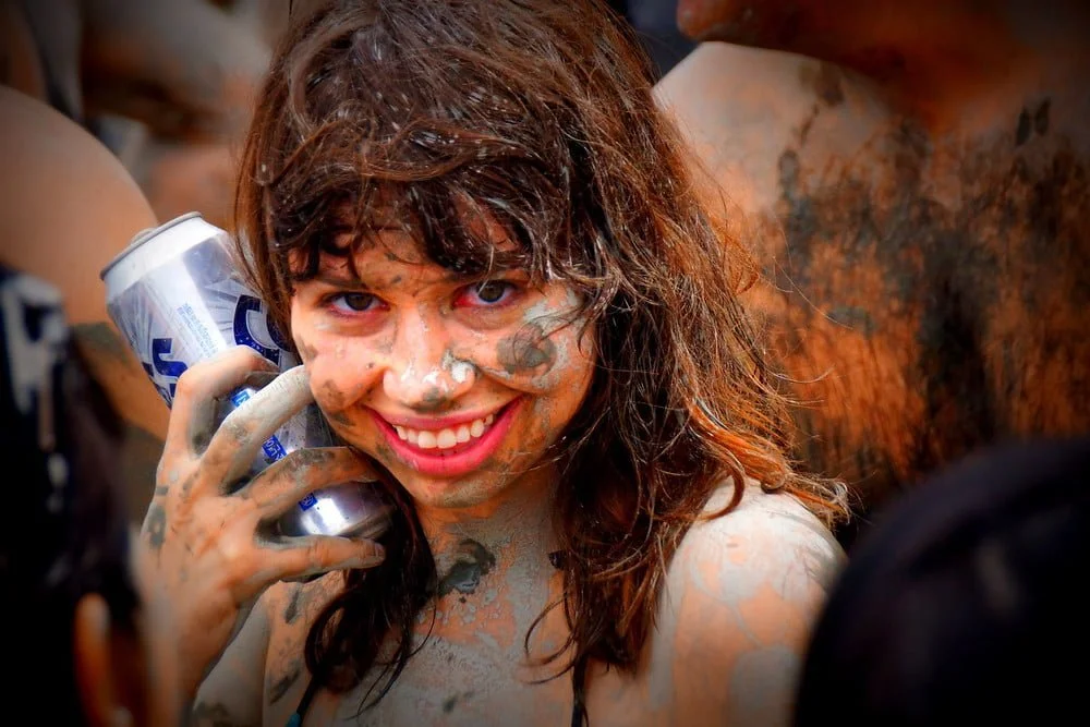 Boryeong Mud Festival in South Korea with a foreigner holding a Cass beer and making a sassy pose