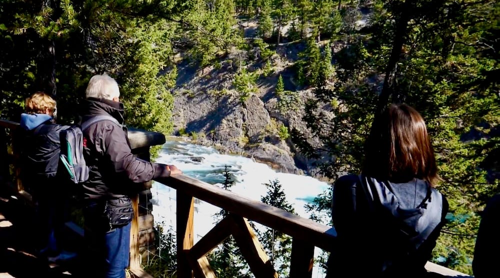 Bow Falls viewpoint along the Bow River Trail, Banff National Park, Alberta, Canada Visitors stand at a wooden railing overlooking Bow Falls rushing through a rocky, tree-lined stretch of the Bow River in Banff National Park, Alberta, Canada.