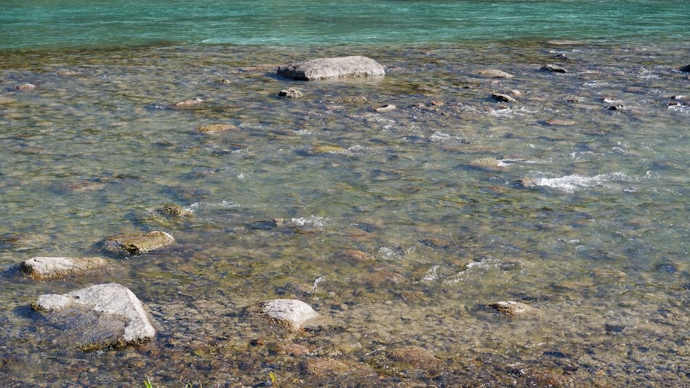 Turquoise water and rocks in the Bow River, Banff, Alberta, Canada Close-up view of the Bow River's turquoise, glacier-fed water flowing over smooth rocks in the shallows near Banff, Alberta, Canada.