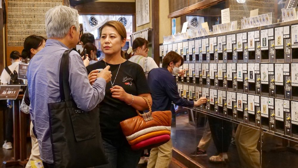 Busy sake tasting room with lots of people trying sake 