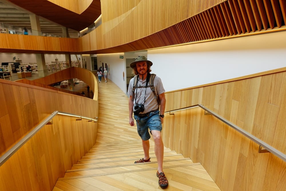 Samuel Jeffery en la escalera de madera dentro de Calgary Central Library, Calgary, Alberta, Canadá Samuel Jeffery sube por una amplia escalera de madera dentro de Calgary Central Library, en Calgary, Alberta, Canadá, rodeado de paredes curvas de madera, balcones y la cálida arquitectura interior de la biblioteca.