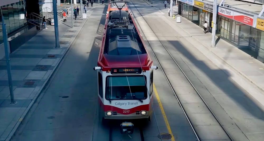 Calgary CTrain Downtown Alberta Canada Public Transit Light Rail for Car-Free City Sightseeing A red-and-white Calgary Transit CTrain travels along street-level tracks in Downtown Calgary, Alberta, Canada, with pedestrians, platforms and overhead electric wires surrounding the light-rail vehicle.