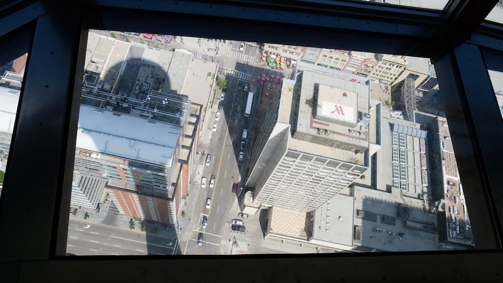 Vista hacia abajo desde el piso de vidrio de Calgary Tower sobre el centro de Calgary, Alberta, Canadá Vista directamente hacia abajo a través del piso de vidrio de Calgary Tower en Calgary, Alberta, Canadá, con calles, techos, vehículos y edificios del centro muy por debajo de la plataforma.