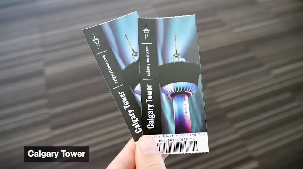 Audrey Bergner sosteniendo entradas para la plataforma de observación de Calgary Tower en Calgary, Alberta, Canadá Audrey Bergner sostiene dos entradas de Calgary Tower en la mano en Calgary, Alberta, Canadá, con el diseño impreso de la torre y los códigos de barras visibles en primer plano.