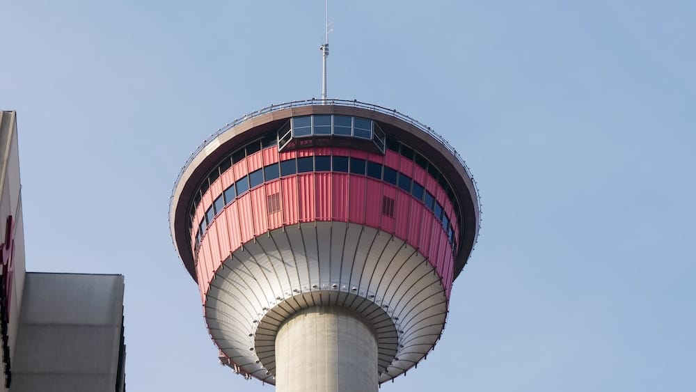 Primer plano del nivel de observación y la estructura superior de Calgary Tower en Calgary, Alberta, Canadá Primer plano de la parte superior de Calgary Tower en Calgary, Alberta, Canadá, mostrando la estructura roja del nivel de observación, ventanas panorámicas, el fuste de hormigón y la antena contra el cielo azul.