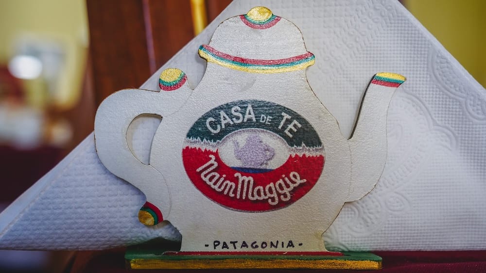 Casa de Té Nain Maggie Trevelin Patagonia Welsh tea house sign Argentina cultural experience Casa de Té Nain Maggie sign shaped like a teapot displayed inside a traditional Welsh tea house in Trevelin Patagonia Argentina, highlighting the iconic tea destination and cultural identity of this Andean Welsh settlement