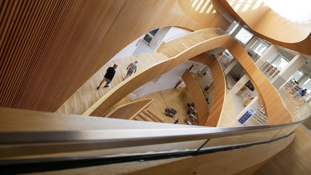 Interior atrium, Central Library, East Village, Calgary, Alberta, Canada The sweeping wood-lined atrium and curved staircases inside Calgary's Central Library in the East Village, with visitors walking through the multi-level open interior, Calgary, Alberta, Canada.