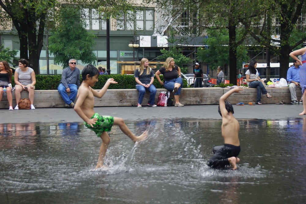 Children playing around and splashing each other at Millennium Park in downtown Chicago