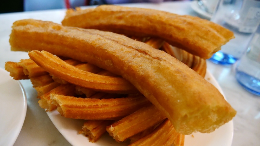 Churros stacked high on a plate in Madrid, Spain