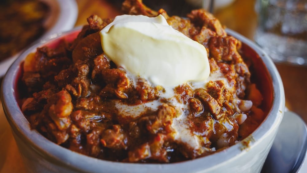Spiced goulash with cream served in Colonia Suiza near Bariloche, Patagonia, Argentina A bowl of rich spiced goulash topped with a generous spoonful of cream is served in Colonia Suiza near Bariloche, Río Negro, Patagonia, Argentina, with tender meat and sauce filling the rustic dish.