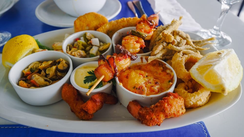 Patagonian seafood platter in Comodoro Rivadavia, Chubut, Argentina featuring shrimp, mussels, calamari, scallops, and fried seafood with dipping sauces, showcasing the diversity of Atlantic coastal cuisine in southern Patagonia.