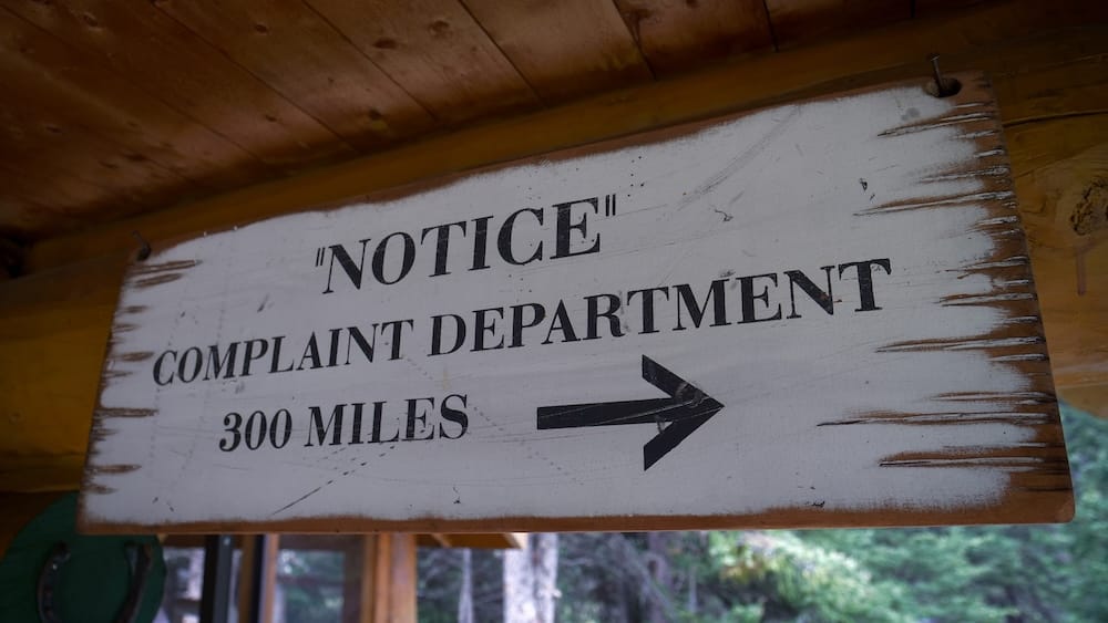Complaint department sign, Halfway Lodge, Banff National Park, Alberta, Canada A weathered wooden sign reading "Notice: Complaint Department 300 Miles" hangs outside the outhouse at Halfway Lodge in Banff National Park, Alberta, Canada, during a six-day backcountry horseback trek.