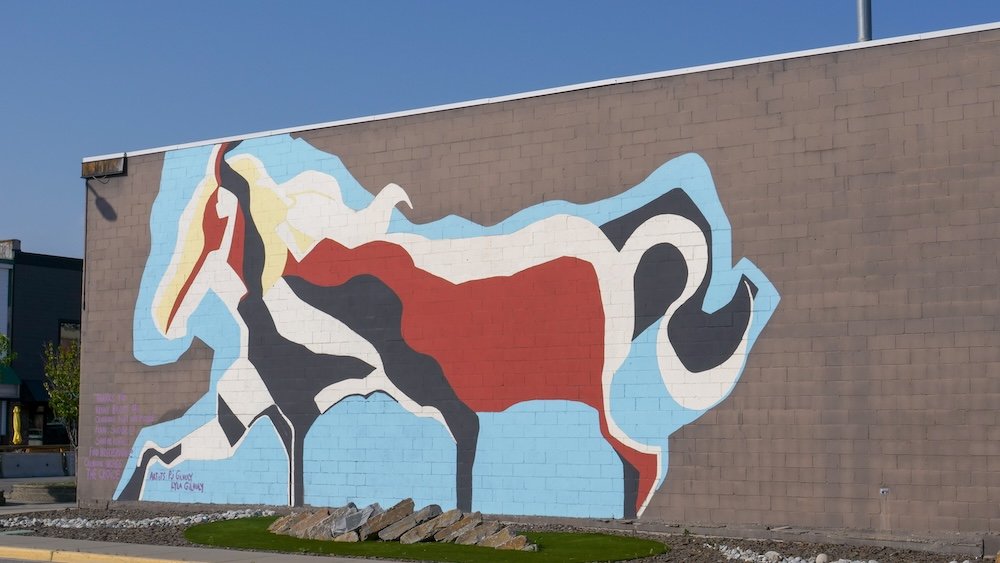 Cranbrook, British Columbia downtown horse mural painted on a brick building, featuring bold abstract shapes and earthy colours that reflect the region’s western heritage, creative spirit, and small-city arts scene during summer.