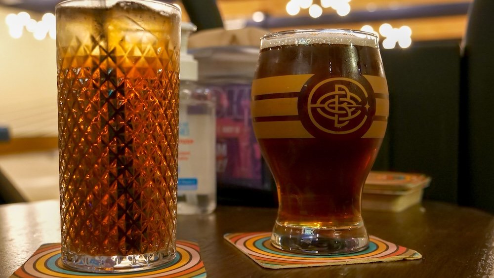 Cranbrook BC drinks at Encore Brewing during a relaxed date night, featuring a pint of house beer and a tall glass of iced tea on the table, highlighting casual craft drinks enjoyed alongside bowling, pizza, and a laid-back evening indoors.