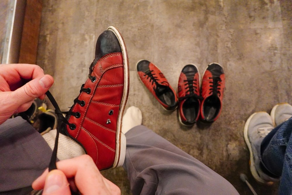 Cranbrook, British Columbia: Nomadic Samuel laces up bowling shoes at Encore Brewing, getting ready for a casual date night of bowling, pizza, and craft beer—one of the most fun and laid-back evening activities in Cranbrook.