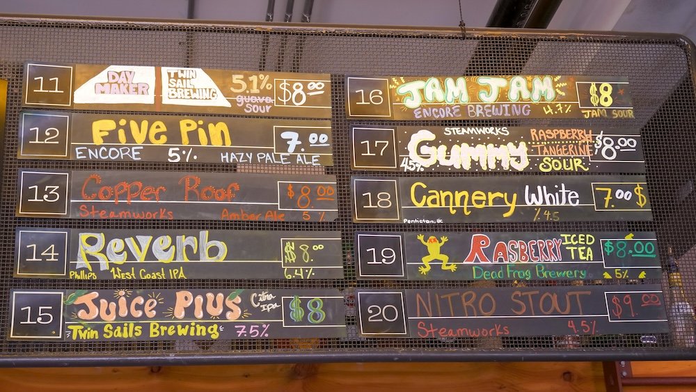 Cranbrook, British Columbia craft beer menu at Fire Hall Kitchen & Tap showing the second half of the tap list with BC local beers, including hazy pale ales, amber ales, sours, white ales, stouts, and rotating seasonal brews from breweries across British Columbia, displayed on a colorful hand-drawn chalkboard board.
