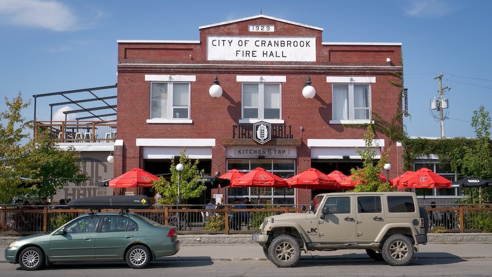 Cranbrook, British Columbia Fire Hall Kitchen & Tap exterior with vehicles parked outside the historic brick fire hall, showing the repurposed 1929 building that now serves as a popular restaurant stop for travelers passing through town.