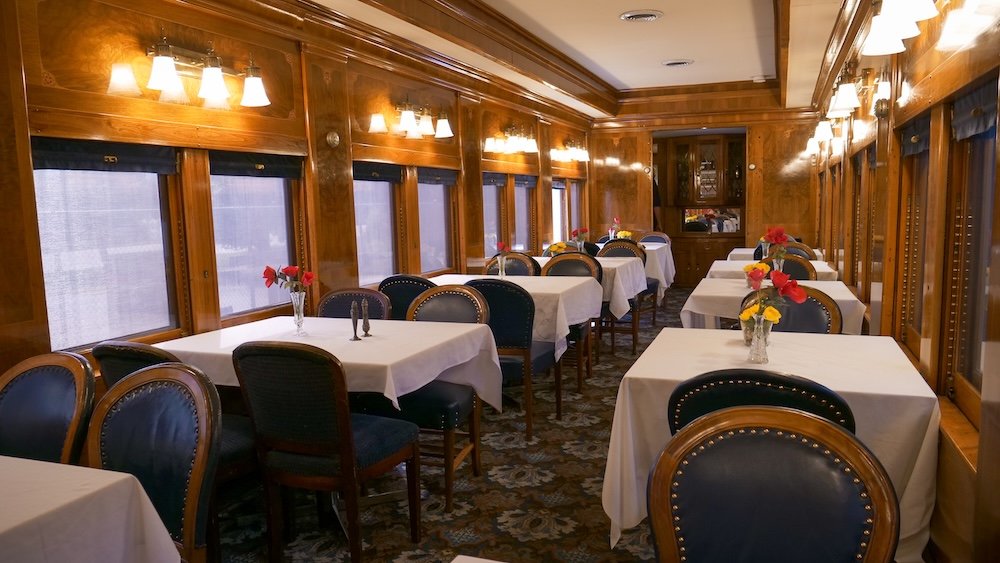 Historic dining car interior on the toddler train tour at the Cranbrook History Centre in Cranbrook, British Columbia, featuring restored wood paneling, table settings, and seating that showcase classic Canadian railway travel heritage.