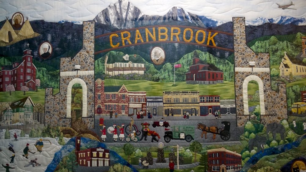 Textile artwork mural at the Cranbrook History Centre A vibrant textile artwork at the Cranbrook History Centre depicts historic buildings, mountain scenery, local landmarks, and community life, showcasing Cranbrook’s heritage through detailed fabric textures and colorful stitched storytelling.