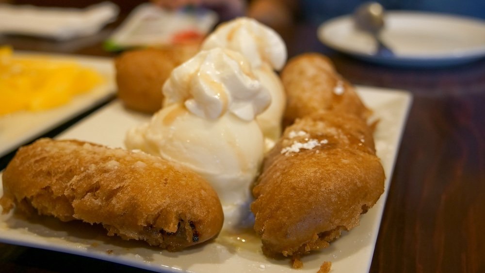 Deep-fried banana dessert at Family Thai Restaurant in Cranbrook, British Columbia, featuring crispy golden bananas served warm with vanilla ice cream and whipped cream, photographed as a sweet and indulgent finish to an authentic Thai comfort-food dinner.