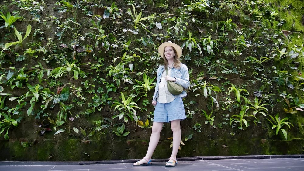 Audrey Bergner junto a la pared vegetal de Devonian Gardens, Calgary, Alberta, Canadá Audrey Bergner está frente a una densa pared vegetal en Devonian Gardens, Calgary, Alberta, Canadá, rodeada de vegetación tropical dentro del jardín interior ubicado en pleno centro.