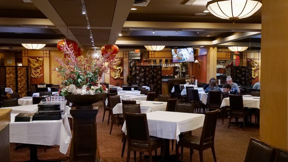 Dining Room Interior at Silver Dragon Restaurant, Chinatown, Calgary, Alberta, Canada The dining room at Silver Dragon Restaurant in Chinatown, Calgary, Alberta, Canada, with red lanterns, gold dragon wall panels, white-clothed tables, and diners seated near the bar.