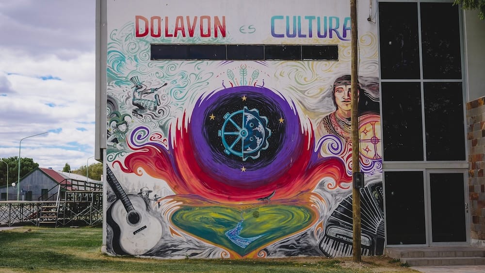Dolavon Patagonia cultural mural street art showcasing local identity and creative spirit in Chubut Argentina Dolavon, Chubut Patagonia — colorful mural reading “Dolavon es Cultura” with vibrant artwork of music, nature, and local identity painted on a town building, reflecting the creative spirit and cultural pride of this overlooked Patagonian community.