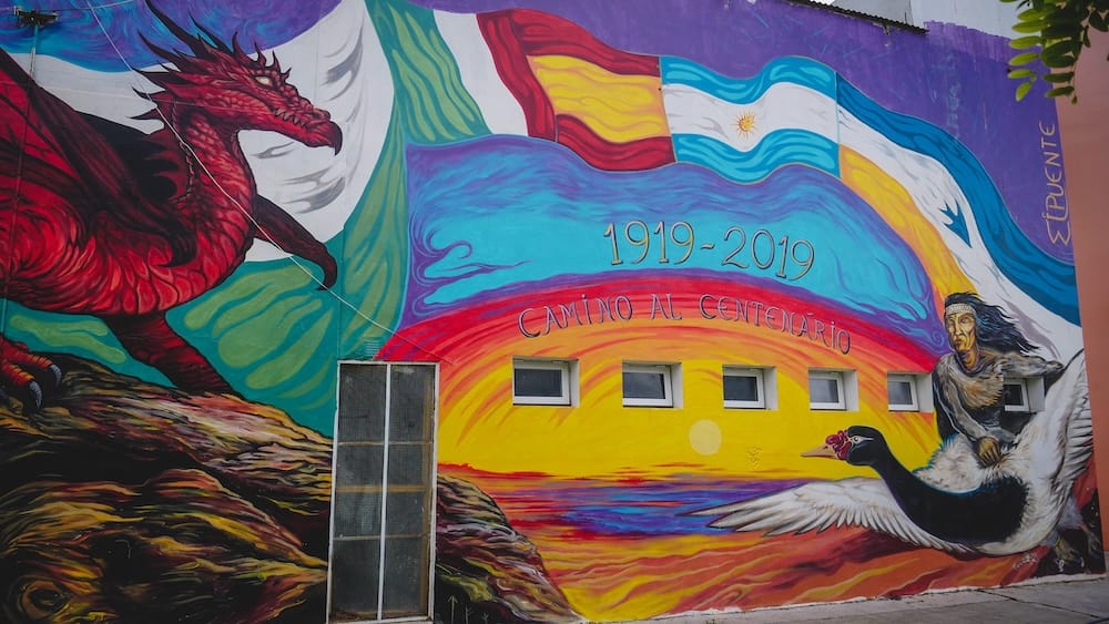 Colorful Welsh-Patagonian mural in Dolavon featuring a red dragon, Argentine flag, and historical imagery, symbolizing cultural identity and the enduring legacy of Welsh settlers in southern Argentina.