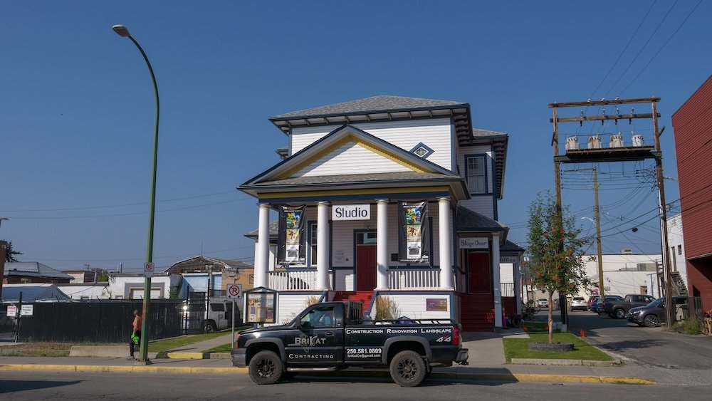 Downtown Cranbrook, British Columbia, featuring a distinctive heritage-style building with a columned façade and colorful banners, reflecting the small-city character, arts presence, and walkable streetscape found in the heart of Cranbrook.