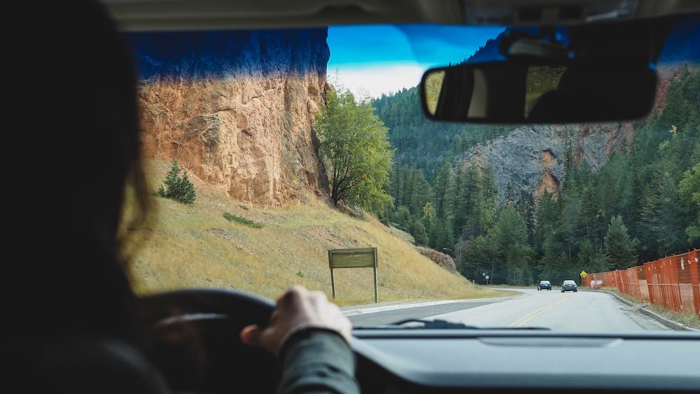 Driving the mountain highway toward Kootenay National Park, Canadian Rockies A driver's view through the windshield of a mountain highway winding past rocky cliffs and evergreen forest on the drive between Banff and Kootenay National Parks in the Canadian Rockies.
