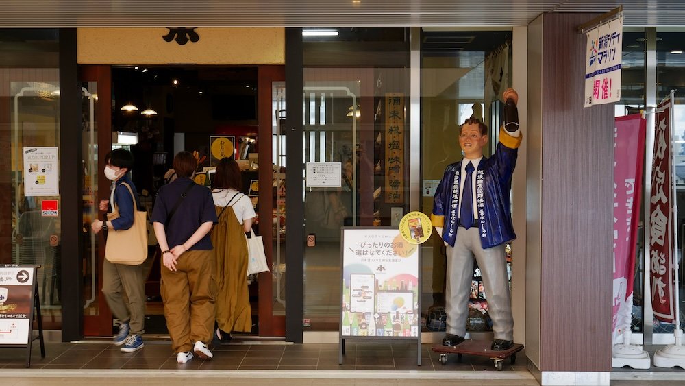 Drunk sake man holding a bottle outside of a sake store in Japan 