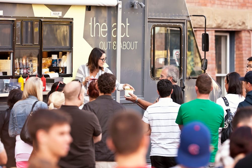 Edmonton food truck and outdoor street-food scene in Alberta, Canada A crowd gathers at an Edmonton food truck in Alberta, Canada, as a vendor serves food through the open service window during an outdoor street-food event.