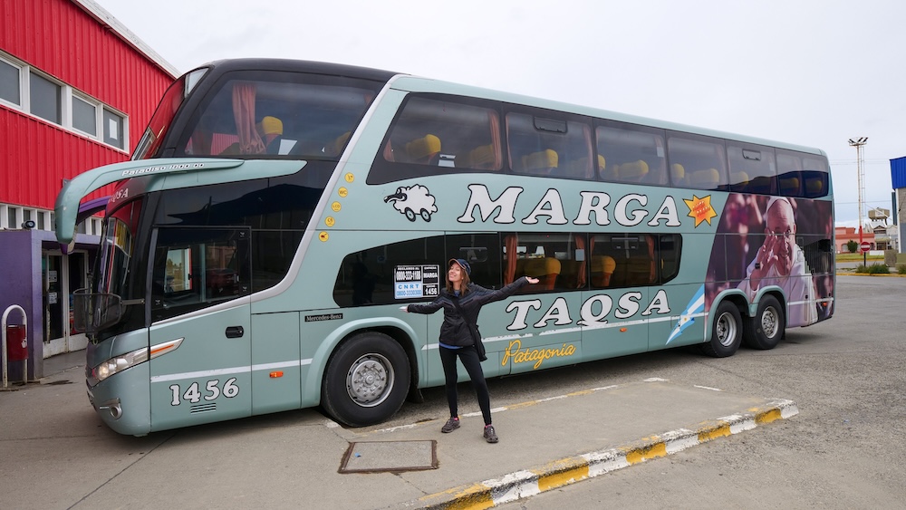El Calafate, Patagonia: Audrey Bergner stands excited beside a Marga Taqsa bus, ready to travel from El Calafate to El Chaltén, highlighting the classic transport link into Argentina’s famous hiking capital.