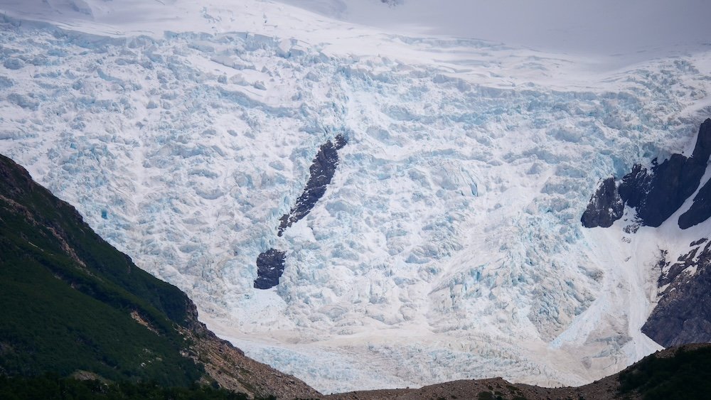 El Chaltén, Argentina glacier within Los Glaciares National Park, showing vast blue ice fields and fractured crevasses surrounded by rugged Patagonian mountains—illustrating how this trekking town is part of a much larger protected glacial landscape.