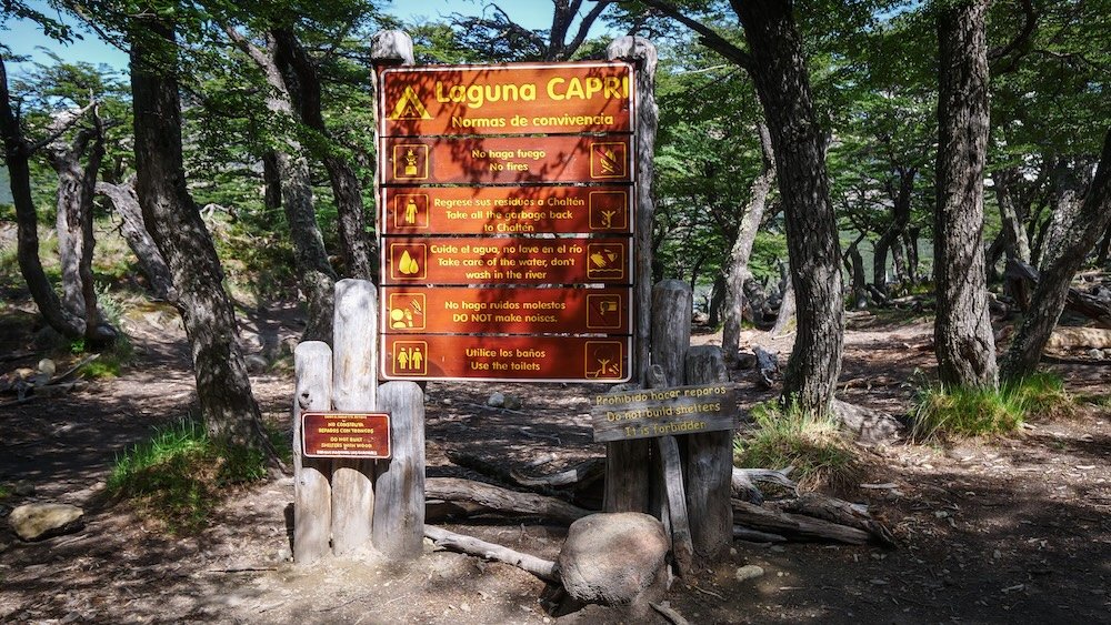 El Chaltén, Argentina trail sign for Laguna Capri displaying park rules and hiking guidelines inside Los Glaciares National Park, marking the approach to one of the most popular and accessible viewpoints with Fitz Roy scenery.
