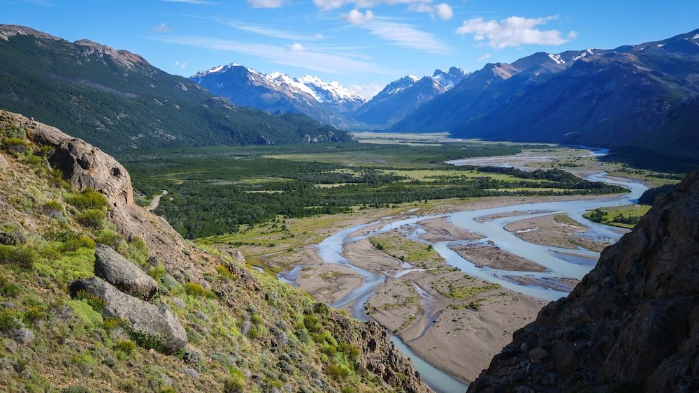 El Chaltén, Argentina view from Mirador Río de las Vueltas overlooking the braided Río de las Vueltas river, wide green valley floor, and surrounding Patagonian mountains, showcasing one of the easiest short hikes with a big scenic payoff near town.
