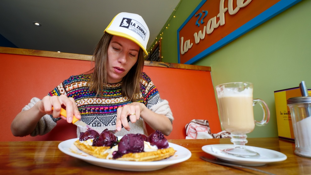 Audrey Bergner enjoying waffles at La Waflería café in El Chaltén, Patagonia, a cozy spot where visitors can relax with sweet comfort food and warm drinks after sightseeing around Mount Fitz Roy without committing to long hikes.