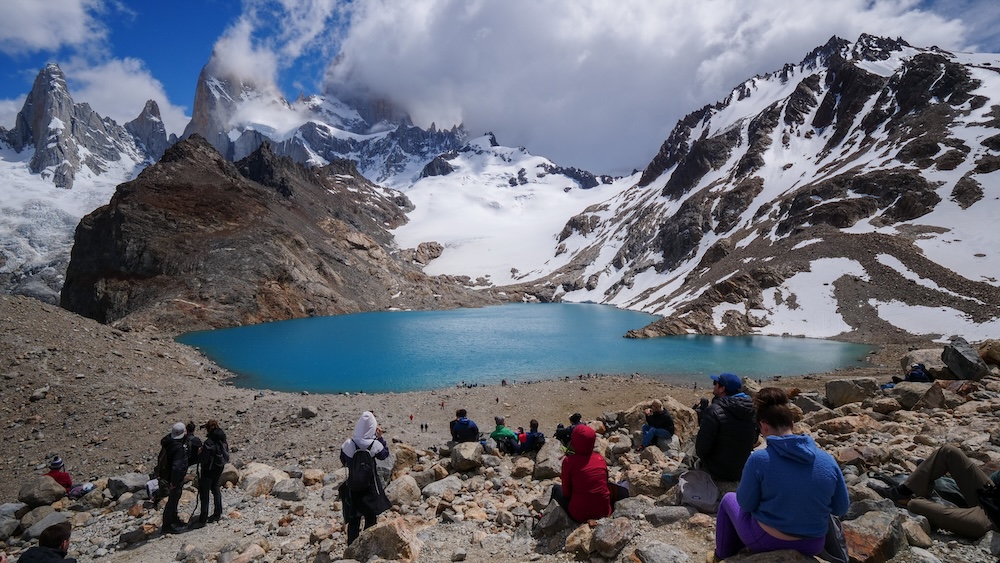 Crowds at Laguna de los Tres viewpoint beneath Mount Fitz Roy in El Chaltén Patagonia El Chaltén Patagonia hikers crowding the Laguna de los Tres viewpoint beneath Mount Fitz Roy in Los Glaciares National Park, illustrating how busy the famous payoff point becomes later in the day when trekkers arrive on Patagonia’s most popular hike.