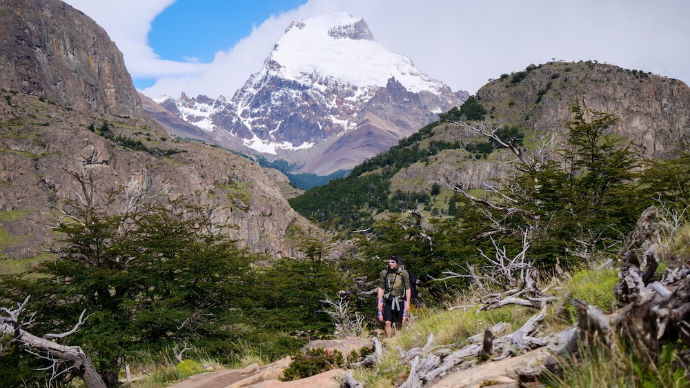 Hiker on the Laguna Torre trail in El Chaltén with Cerro Torre in Los Glaciares National Park El Chaltén Patagonia hiker walking the Laguna Torre trail toward Cerro Torre in Los Glaciares National Park, showing the rugged valley terrain and wilderness conditions trekkers navigate on one of the region’s most popular day hikes.